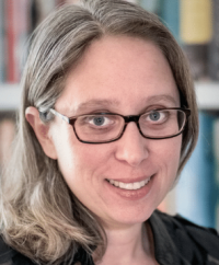 Smiling woman with glasses poses in front of a bookcase
